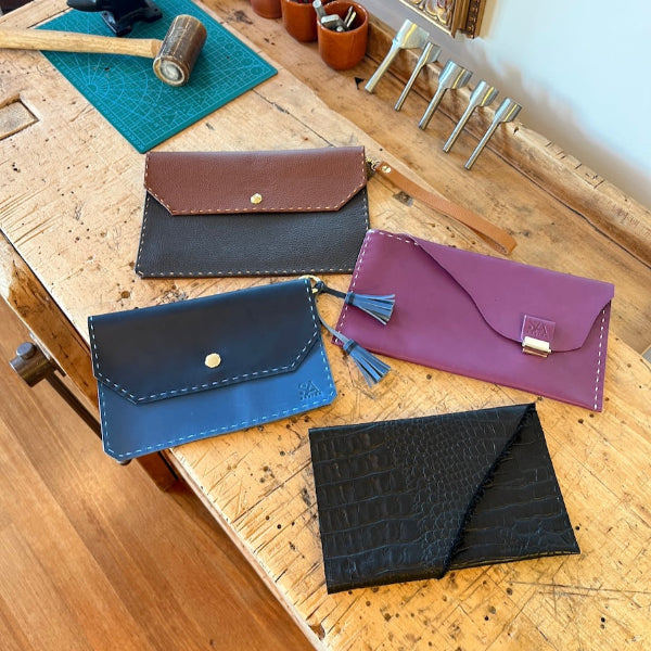Collectie van handgenaaide leren clutches in verschillende kleuren uit de workshop van SA Design