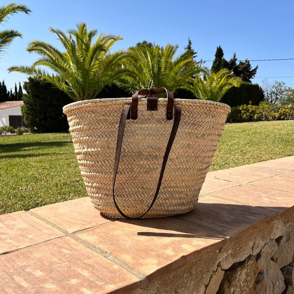 Groten rieten strandtas uit de Valencia collectie op muurtje