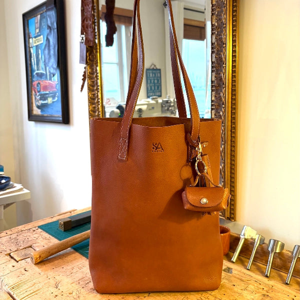 Volledig beeld van een leren tote van duurzaam leer met een bagcharm en leren kwast