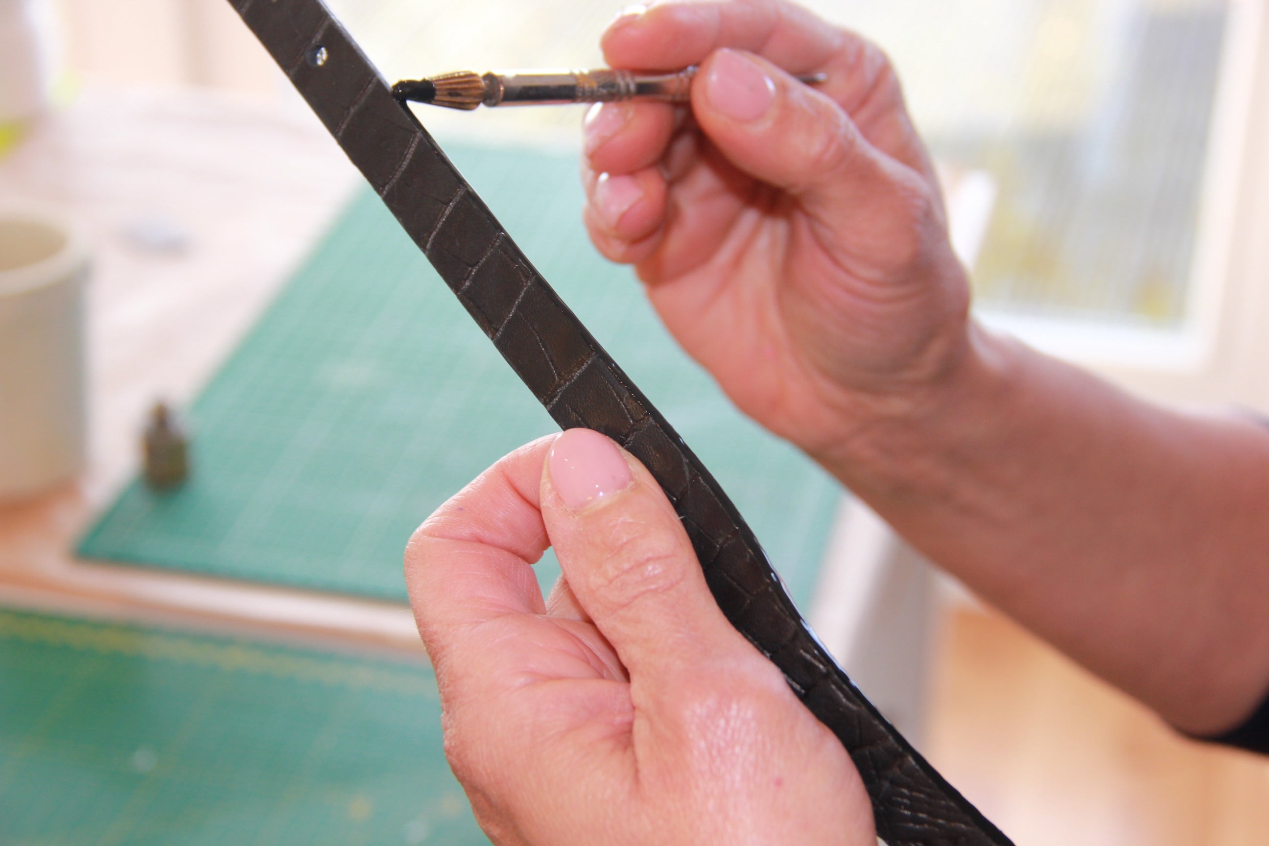 Verven van de randen van een handgemaakte leren kroko armband in atelier SA Design