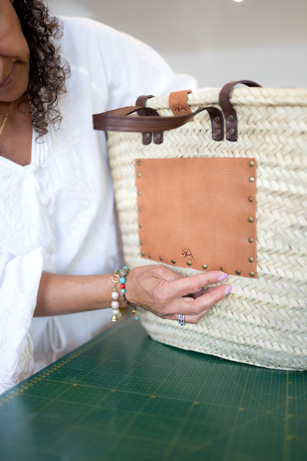 Nina die leren vakken aan het maken is op een rieten tas in het atelier van SA Design