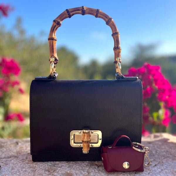 Bag charm in bordeaux bij de Madrid Bamboo tas in bruin op stenen muurtje