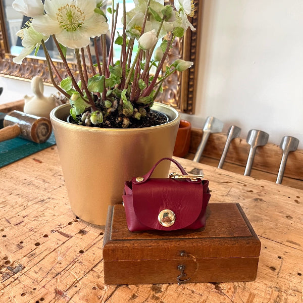 Bag charm in bordeaux op de werkbank in het leeratelier van SA Design