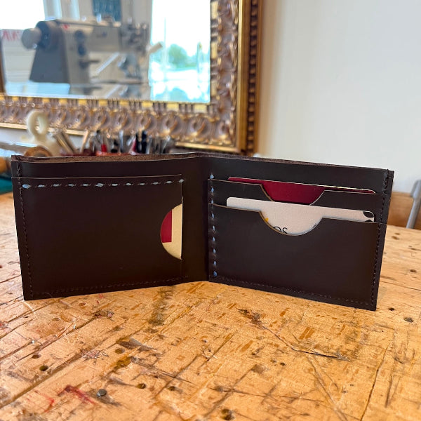 Handgemaakte portefeuille in donkerbruin leer voor biljetten en pasjes in donkerbruin leer staand opengeslagen