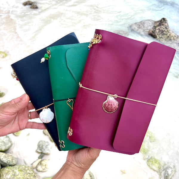 Collectie leren notebooks in de hand op strand