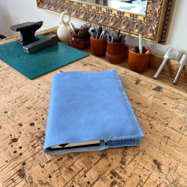 Handgemaakte lichtblauwe journal van natuurlijk gelooid kalfsleer uit Toscane op de werkbank