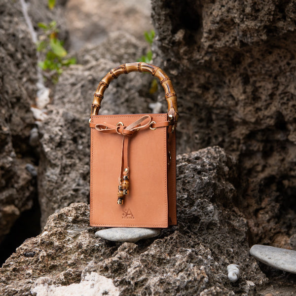 Leren crossbody tas uit de Madrid Bambu collectie op een rots in de Cariben