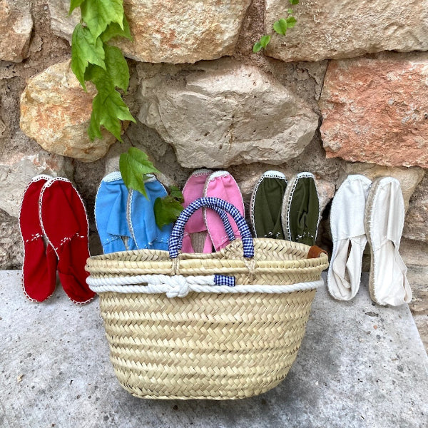 Spaanse espadrilles tegen een muur met rieten tasje
