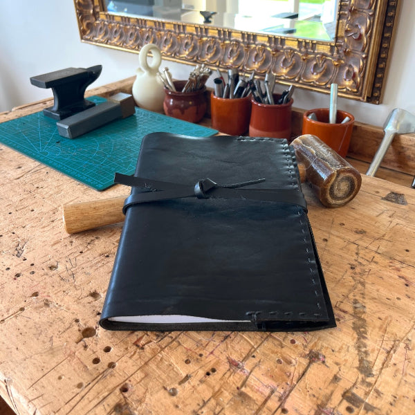 Leren notebook in zwart kalfsleer op de werkbank bij SA Design