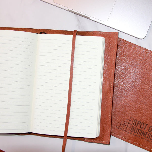 Handgemaakte leren notebook cover in camel met logo en muismat met logo opengeslagen op tafel