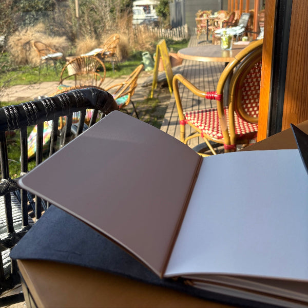 Leren notebook A5 met goudvergulde bedels opengeslagen op tafel zodat je het design goed ziet