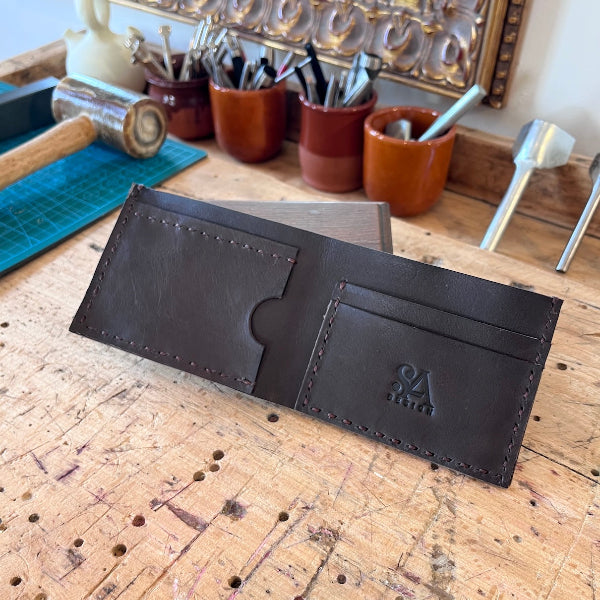 Leren handgemaakte portefeuille in donkerbruin opengeslagen op de werkbank