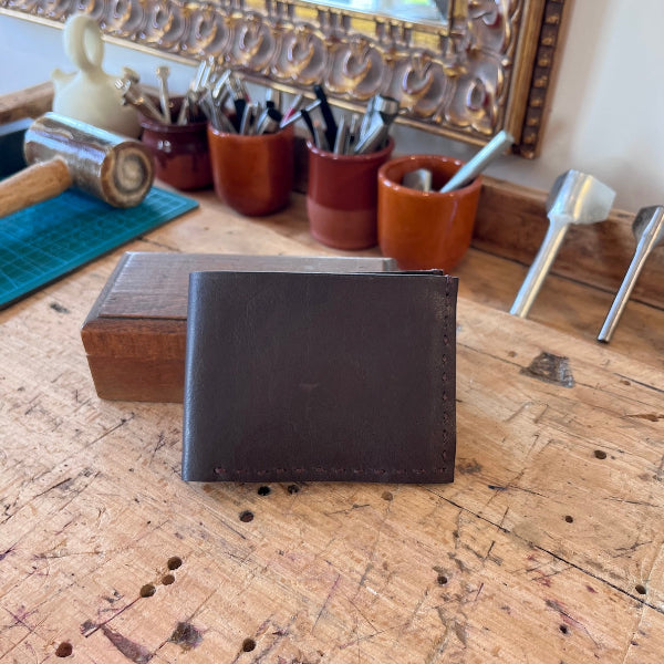 Leren handgemaakte portefeuille in donkerbruin voorzijde op werkbank