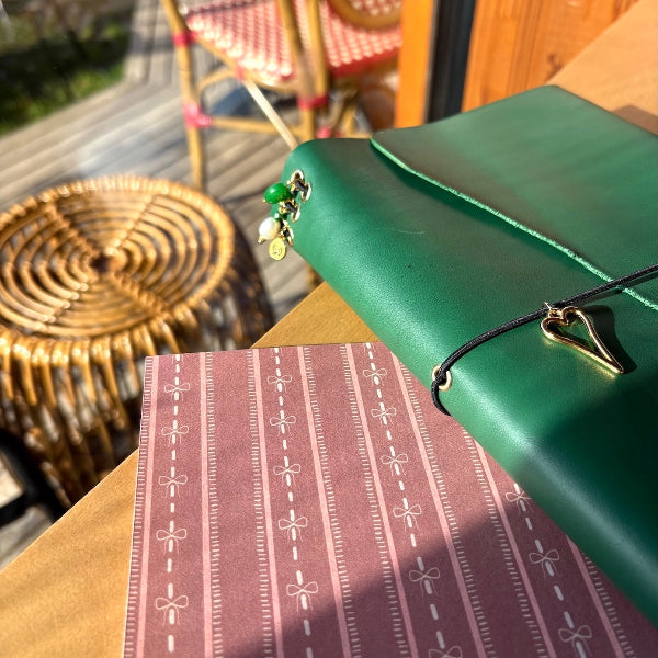 Notebook A5 met goudvergulde bedels in groen met grote hartbedel op tafel met bordeaux designpapier