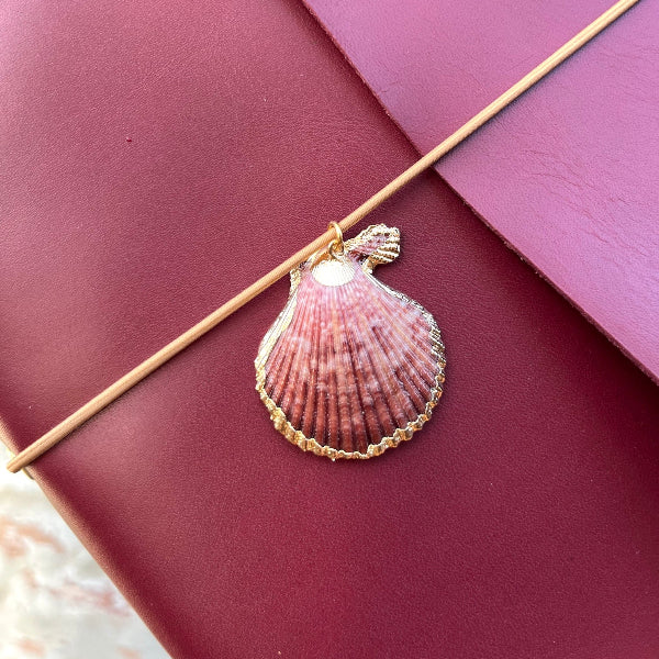 Notebook A5 met goudvergulde bedels in bordeaux met close up van schelpbedel