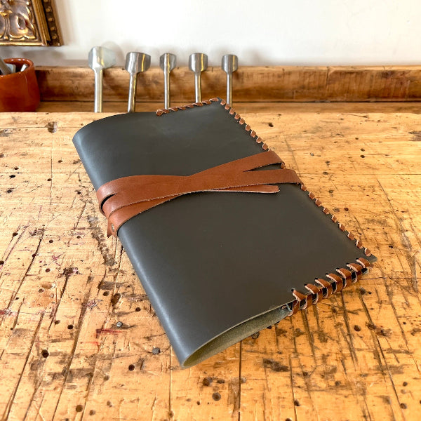 Handgemaakte notebook met leren lint en lint omslag op werkbank vanaf zijkant