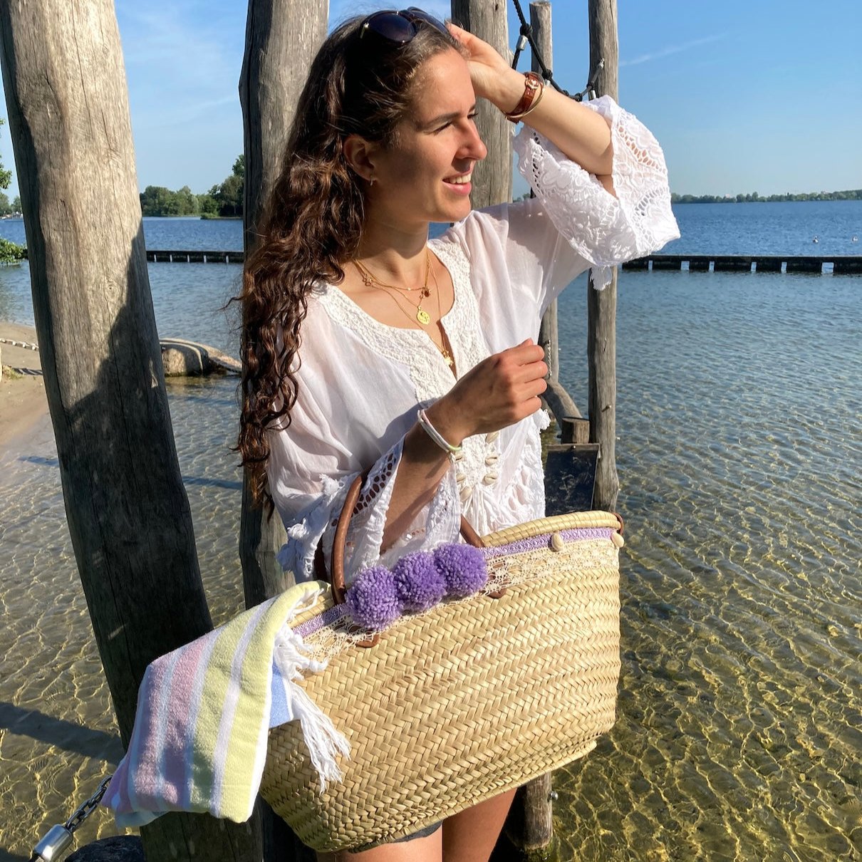 Handgemaakte grote rieten strandtas uit de Ibiza collectie met pompons en schelpen aan arm