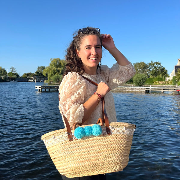 Rieten strandtas die je aan de hand en ook als schoudertas kunt dragen met kant, schelpen en aqua pompons op de steiger