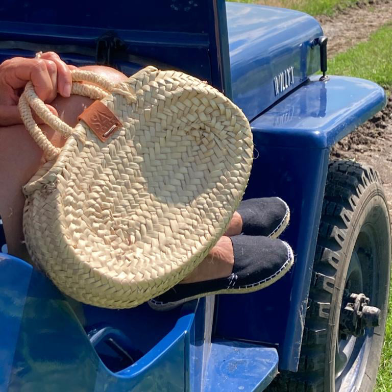 Kleine rieten tas in ovale vorm aan de hand