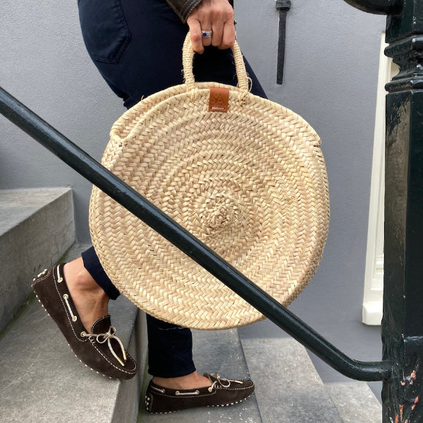 Ronde rieten tas aan de hand op een Amsterdamse trap