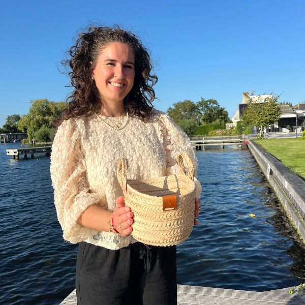 Rieten tasje in de handen van Sofia op de steiger van voren gezien