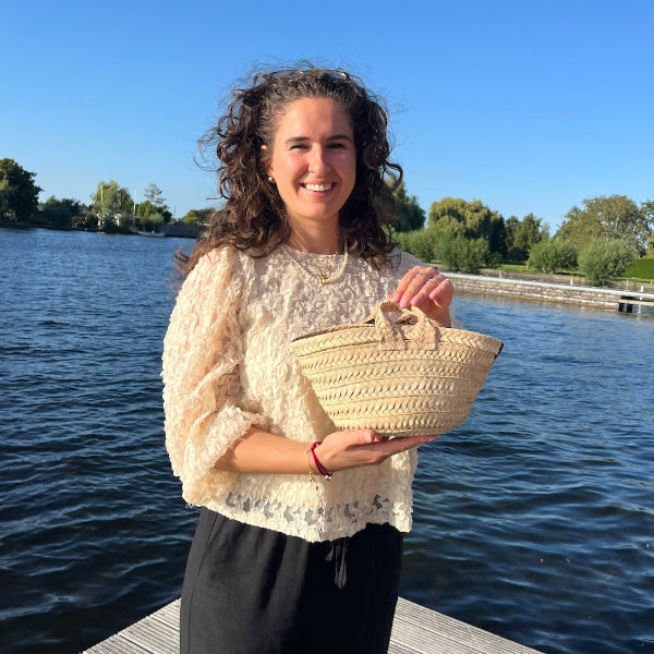 Rieten tasje in de handen van Sofia op de steiger