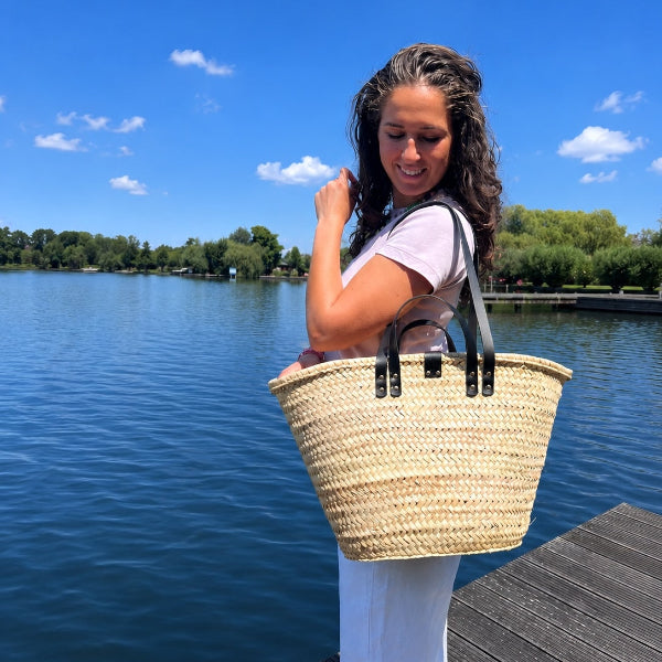 Foto aan de schouder van de rieten strandtas medium met zwarte handvatten en hengsels