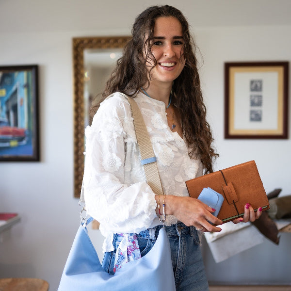 Sofia in atelier met ruime leren shopper in lichtblauw over de schouder