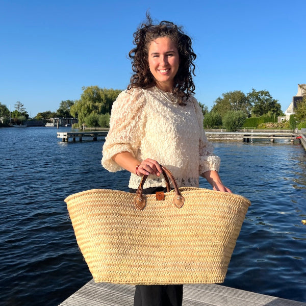 Sofia met de extra grote rieten tas uit de Valencia collectie in de hand op de steiger bij het atelier