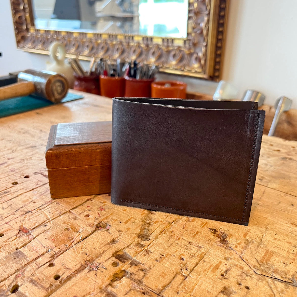 Handgemaakte portefeuille in donkerbruin leer voor biljetten en pasjes in donkerbruin leer staand