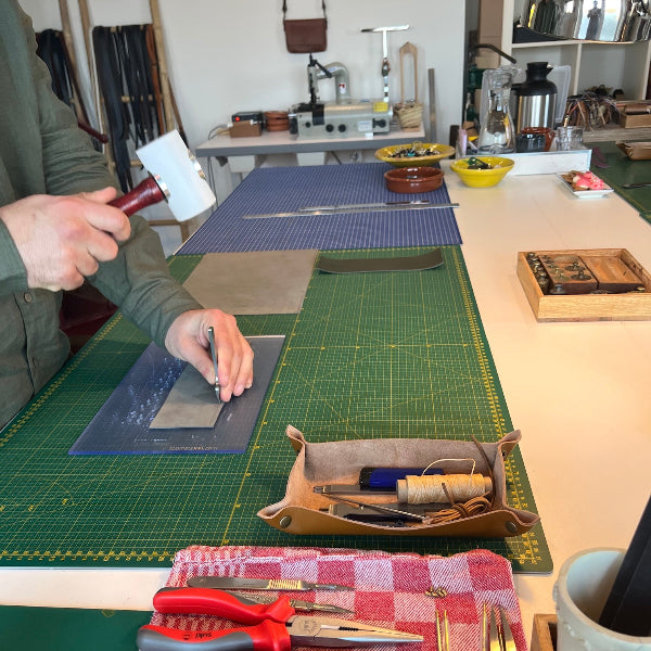 met de hand gaatjes maken voor het naaien van de leren notebook