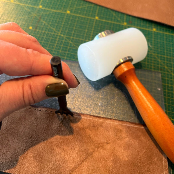 Gaatjes maken in leer met speciale hamer en snijmat in workshop leren notebook cover maken