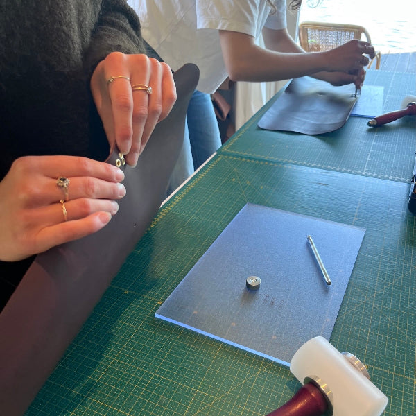 Zeilringen plaatsen in het leer in de workshop gepersonaliseerde leren notebook cover maken