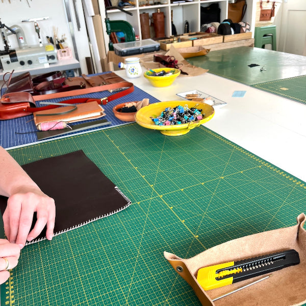 Naaien van donkerbruine notebook met roze garen uit workshop van SA Design