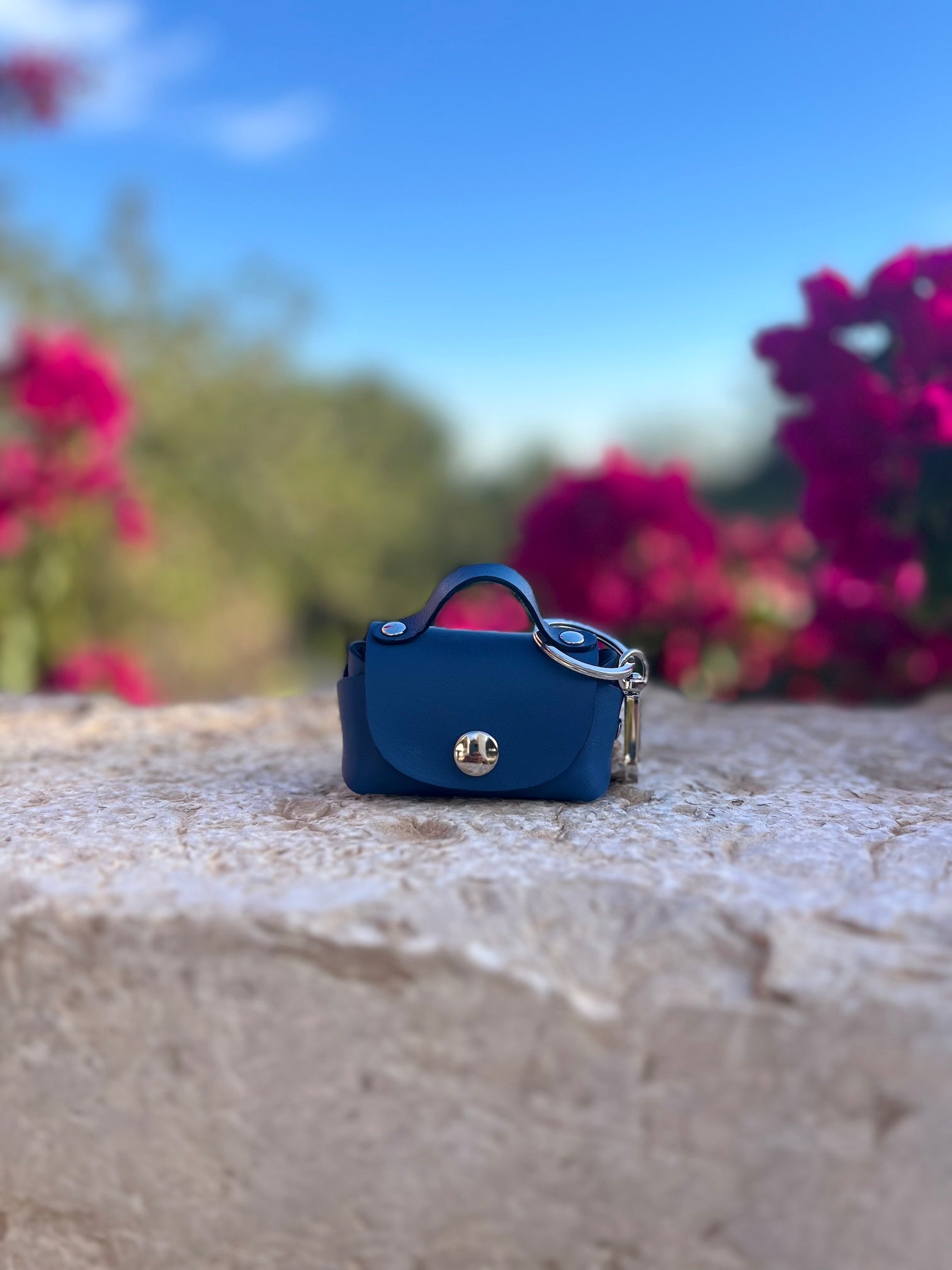 Leren bag charm in donkerblauw op stenen muurtje in Spanje