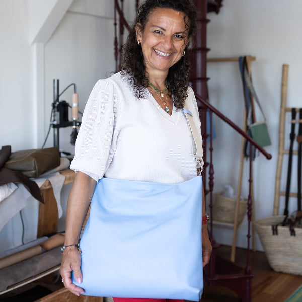 Nina in atelier met ruime leren shopper in lichtblauw over de schouder