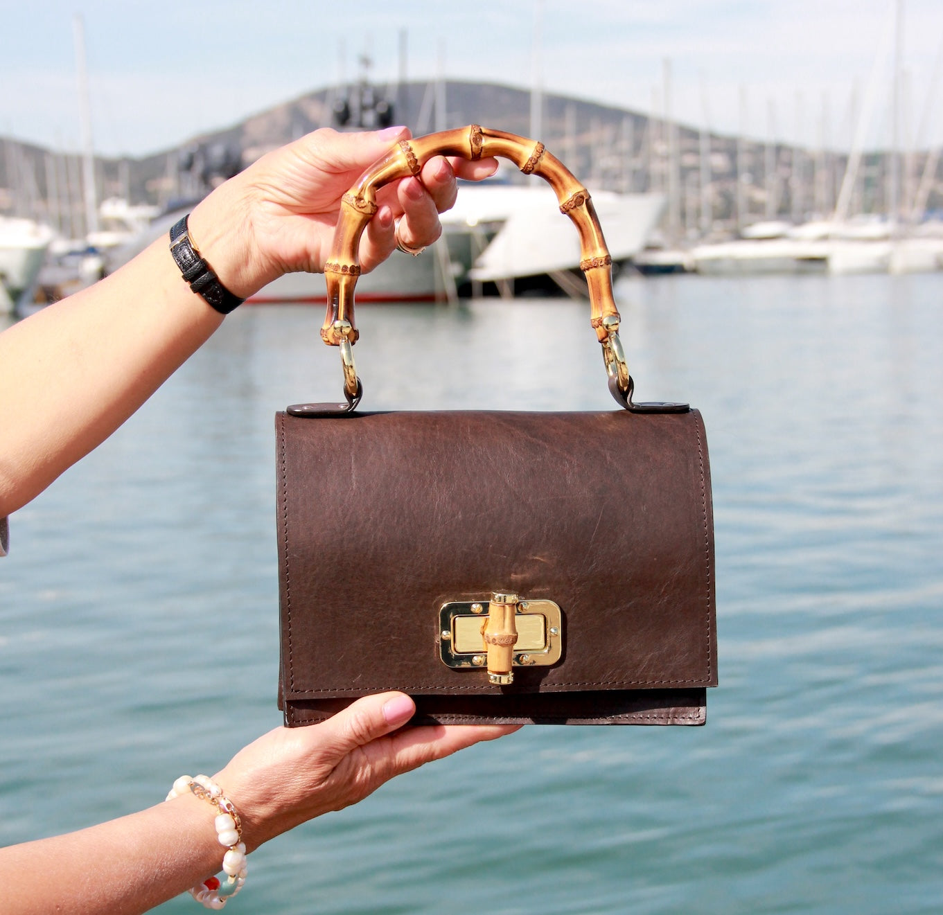 Madrid Bamboo handtas met 3 vakken in donkerbruin aan de hand in de haven van Saint Tropez