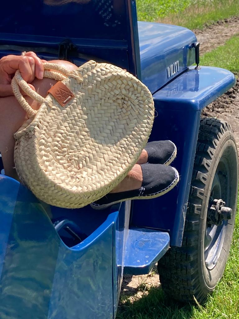 Rieten tas in ovale vorm in de hand in een oude Willys jeep