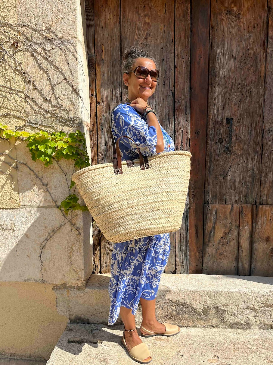 Grote rieten strandtas met leren handvatten en hengsels aan de schouder van Nina in Spanje