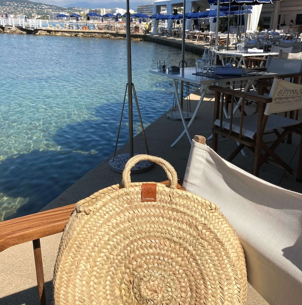 Sofia met een Handgemaakte rieten schoudertas in ronde vorm in Saint Tropez