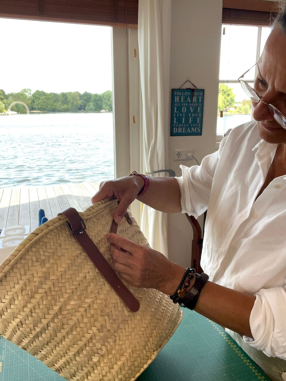 Nina die werkt aan een rieten tas in het atelier van SA Design