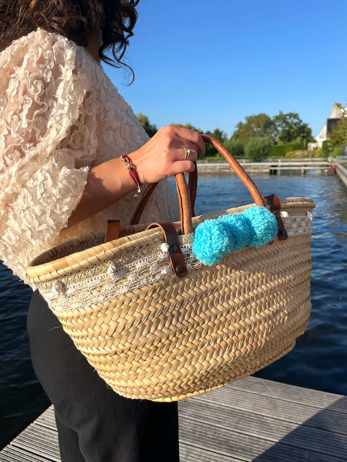 Rieten tas in Ibiza style met pompons en schelpen aan de hand van Sofia
