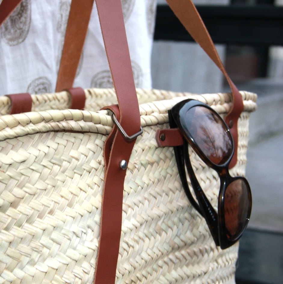 Achterzijde  met zonnebril aan leren buitenlus van Sevilla rieten tas met leren vakken