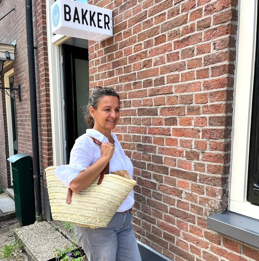 Nina bij de bakker met de Sevilla rieten tas