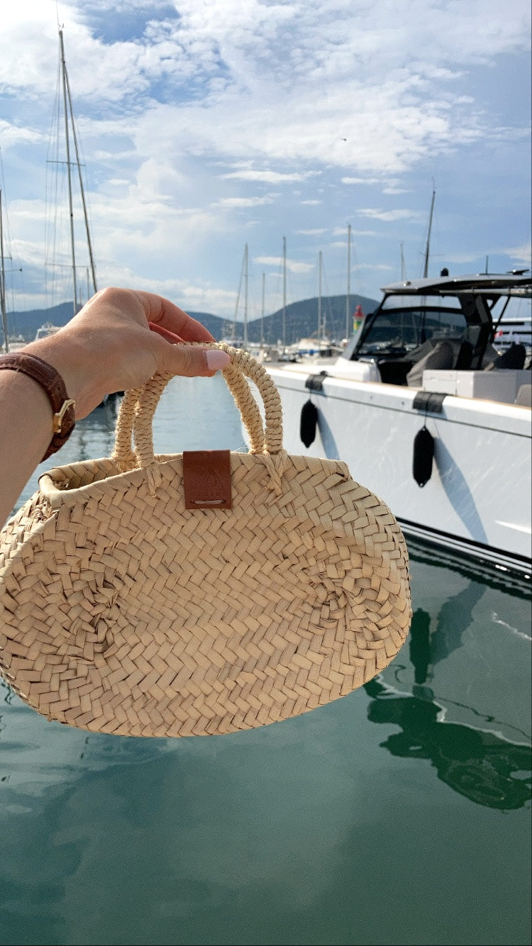Rieten tas in ovale vorm in de hand bij de haven van Saint Tropez
