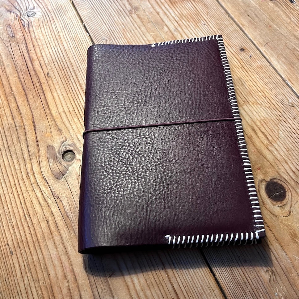 Handgemaakte leren notebook die is gemaakt in een workshop op locatie in bordeaux met lichtroze garen